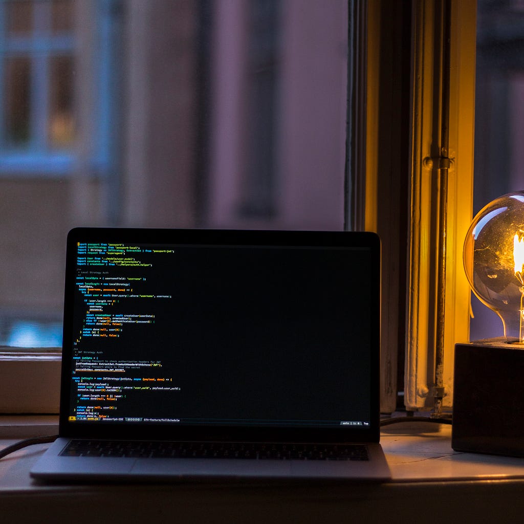 A computer on a desk, with code on the computer display.